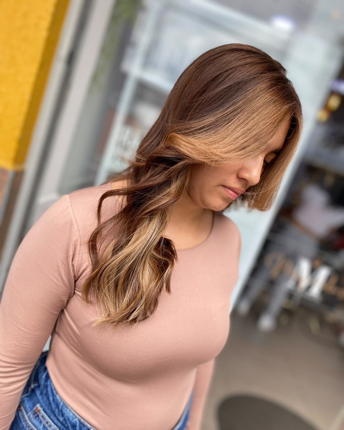 Melena larga castaña con balayage caramelo y reflejos miel, vista de perfil