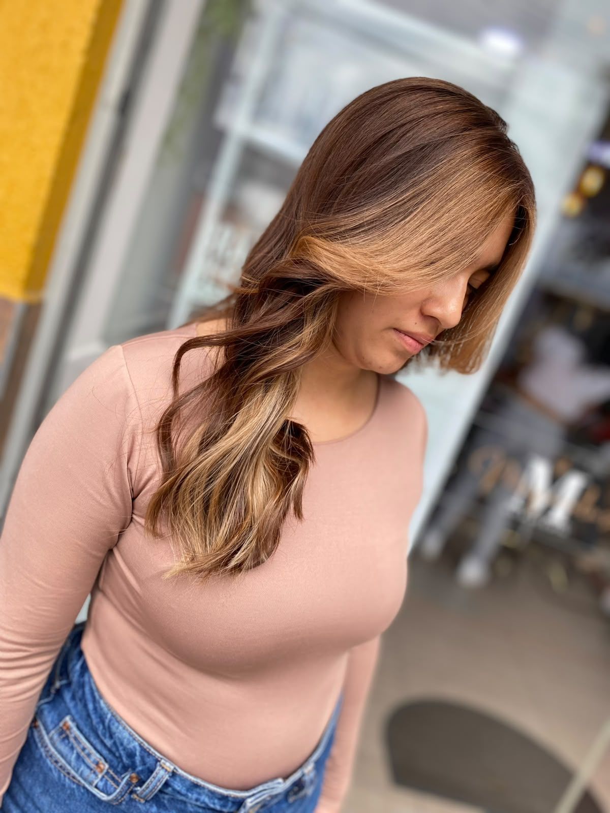 Melena larga castaña con balayage caramelo y reflejos miel, vista de perfil