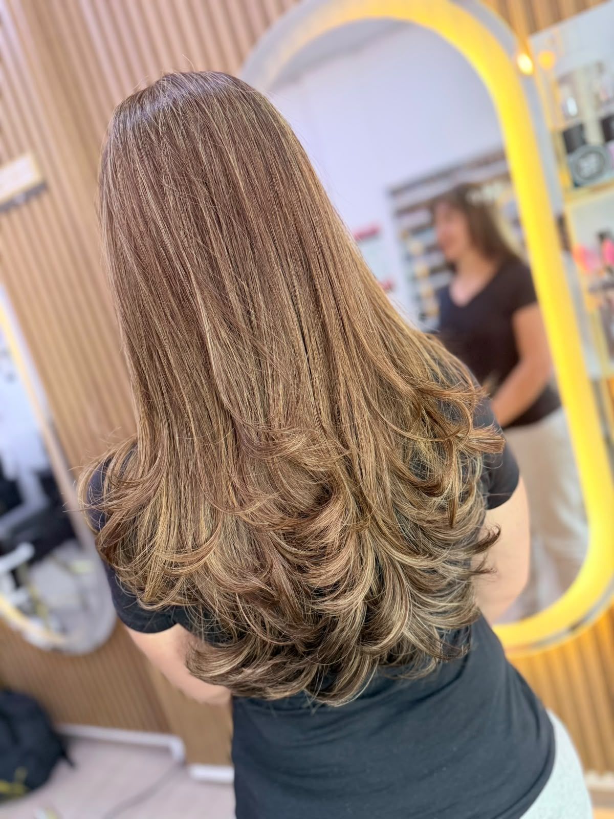 Melena larga en capas con balayage caramelo dorado y puntas más claras, vista trasera