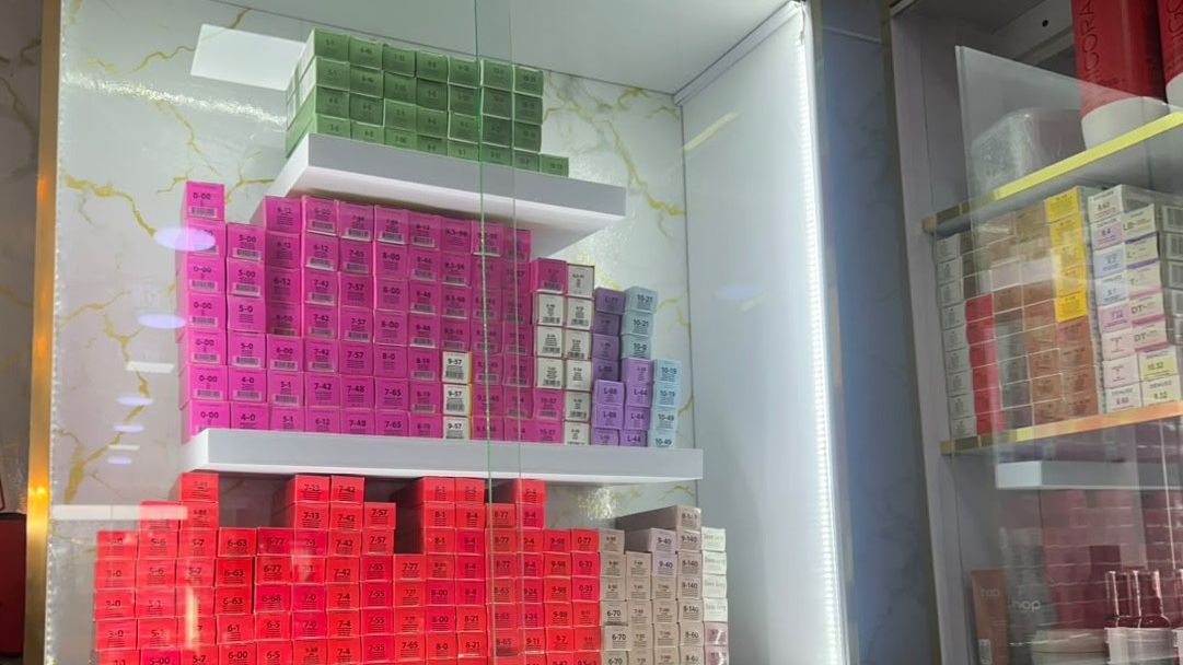 Vitrina iluminada con cajas de tintes profesionales ordenadas por tono