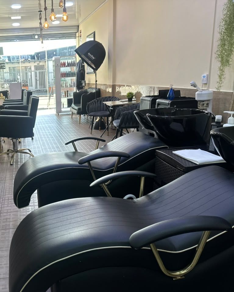 Área de lavado de Maquiavelo's Hair Studio con sillones reclinables negros y lavacabezas